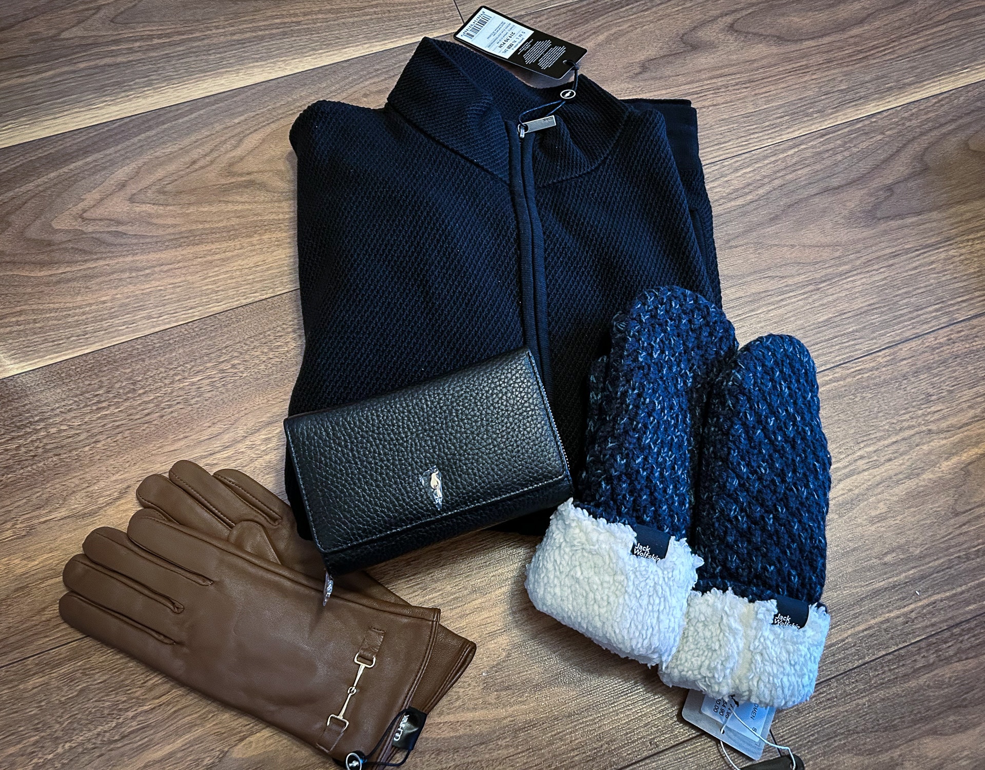 a pair of gloves and a sweater on a wood surface
