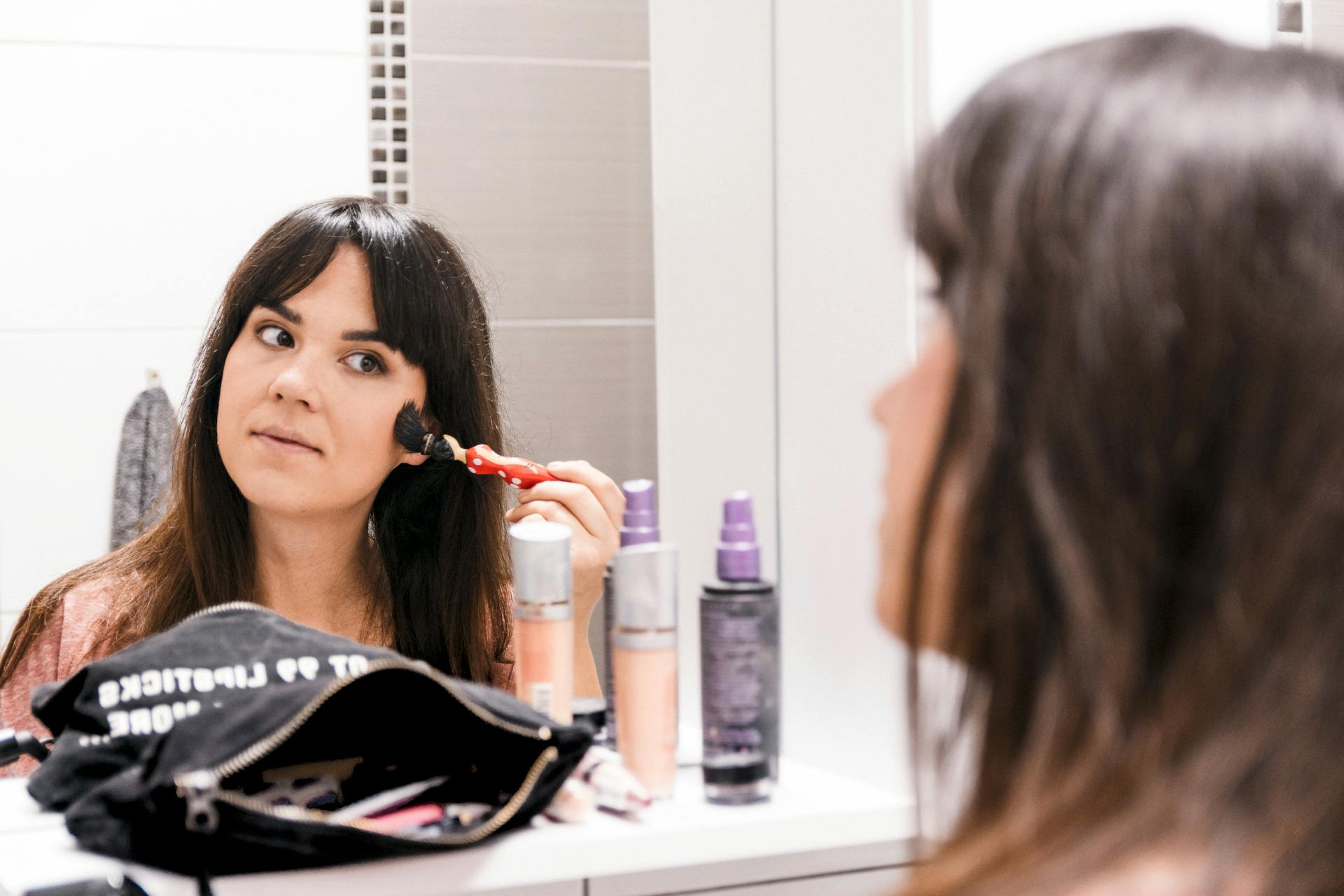 a woman applying makeup in front of a mirror