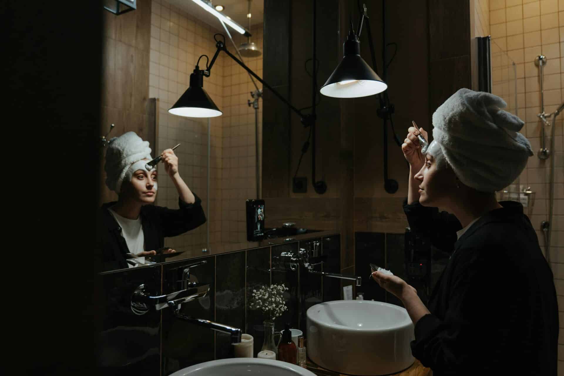 Kobieta nakłada krem na czoło przy lustrze wieczorem