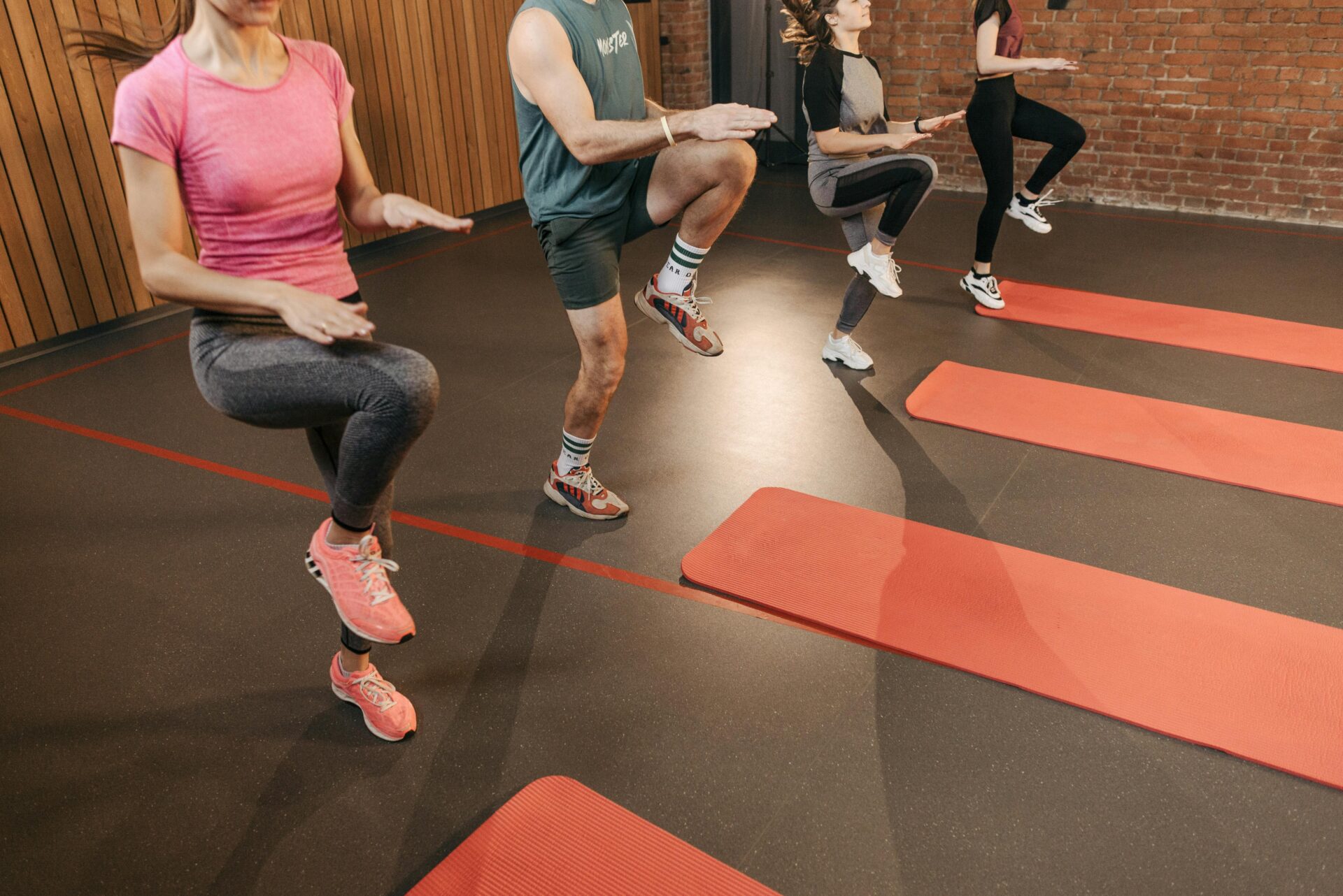 Osoby ćwiczące na macie w grupie, wykonujące trening cardio