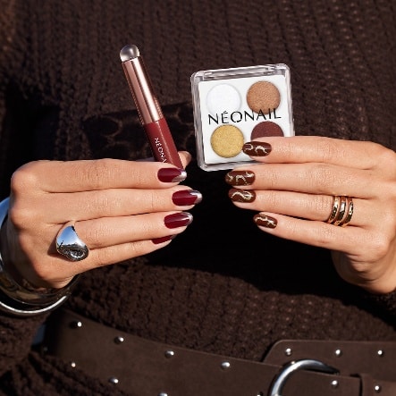 Dłonie z bordowym manicure oraz paletą prasowanych pyłków NEONAIL